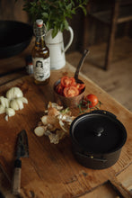 Load image into Gallery viewer, Settle | Netherton Foundry - mid-view of a black spun iron stock pot and its lid set on an antique wooden chopping board alongside chopped onions, a kitchen knife, vine tomatoes, a bottle of olive oil, fresh herbs in an old enamel jug,  in the heritage kitchen of one of Settle's luxury retreats.