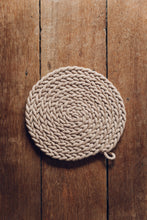 Load image into Gallery viewer, Shop at Settle The Chemists Daughter - overview of a lovely, circle woven trivet handmade from 100% recycled pale cotton, set against antique timbers