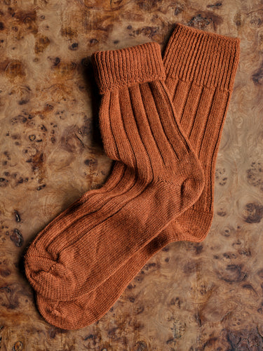 Pair of brown bed socks on a textured wooden surface | Copyright Settle Norfolk UK