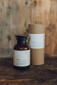 Glass apothecary bottle containing LUNA Bath Salts next to natural cardboard packaging, by Essence + Alchemy, at Settle Norfolk, UK | Copyright Settle Norfolk, UK