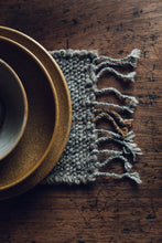 Load image into Gallery viewer, Shop with SETTLE | Cabin Woven - a place setting of handmade ceramics is set on a handwoven table runner made from handspun wool, with tasselled ends and subtle brown on charcoal stripe, on an antique timber table at Settle. 