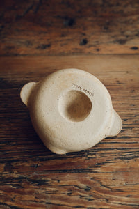 SETTLE | Every Story Ceramics Citrus Juicer - base view of a handmade ceramic citrus juicer showing its makers' mark on its unglazed pale ceramic base, on antique timbers at Settle.