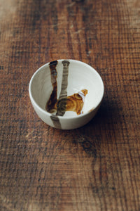 Settle | By Noo Ceramics Brushstroke Dipping Bowl - small handmade pale ceramic bowl with two handpainted brush strokes in chocolate brown, set on antique timbers in one of Settle's luxury retreats.
