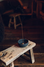 Load image into Gallery viewer, Settle | Ume ~ further view of an elegant black stoneware bowl containing a small gold-coloured incense dome which holds a lighted incense stick, sitting on an antique trestle in one of Settle&#39;s luxury retreats.