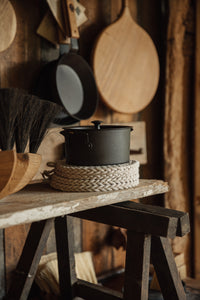 Settle | Netherton Foundry - mid view of a black spun iron stock pot with lid, set on a stack of rope trivets in the enticing space that is Settle's lifestyle store, Settle Shop.  