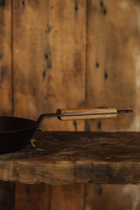 Shop with Settle | Netherton Foundry - close-up on wooden handle of a hand-spun cast iron glamping pan. 
