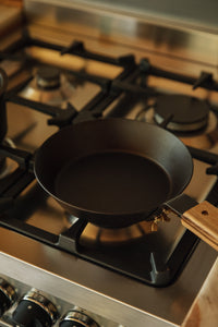 Shop with Settle | Netherton Foundry - overview of a hand-spun cast iron pan with wooden handle in use on a gas hob.