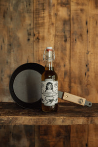 Shop with Settle | Netherton Foundry - hand-spun cast iron pan with wooden handle next to a bottle of Maple Syrup.