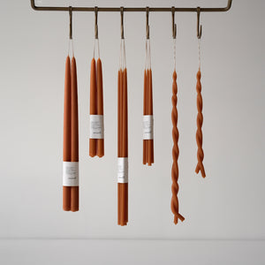 Skar Organics Paprika Candles suspended from meat hooks on a utilitarian rail by Skar Organics 