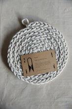 Load image into Gallery viewer, Shop at Settle The Chemists Daughter - overview of a lovely, circle woven trivet handmade from 100% recycled pale cotton, with a label reading The Chemists Daughter  