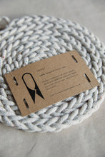 Load image into Gallery viewer, Shop at Settle The Chemists Daughter - closeup of a lovely, circle woven trivet handmade from 100% recycled pale cotton, with a label reading The Chemists Daughter