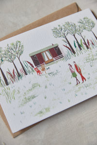 Shop at Settle | Harriet Watson A Walk in the Woods - charming hand illustrated colour greetings card of two guests enjoying a walk in Settle's wooded park, with Carriage No. 2 nestled in the background, set against a pale timber surface.