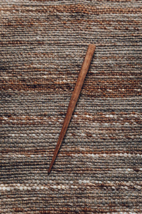SETTLE | Steven Mackus Hand Carved Shawl Pin - a beautiful elegant pin handcarved from walnut wood rests on a natural woven brown wool shawl at Settle.