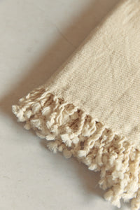 SETTLE | Pico Goods Hand Towel - close-up of a handwoven organic cotton hand towel with tasselled edging in a natural off-white at Settle.