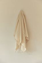 Load image into Gallery viewer, SETTLE | Pico Goods Hand Towel - handwoven organic cotton hand towel in a natural off-white with tasselled edging hung on a wall peg at Settle.