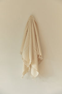 SETTLE | Pico Goods Hand Towel - handwoven organic cotton hand towel in a natural off-white with tasselled edging hung on a wall peg at Settle.
