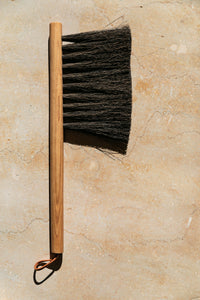 SETTLE | Slow Made Goods - an oak hand brush with natural bristles against a pale marble background at Settle.