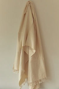 SETTLE | Pico Goods Bath Towel - a handwoven organic cotton bath towel in a natural off-white with tasselled edging is hung on a wall peg at Settle.